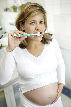 Беременная девушка чистит зубы